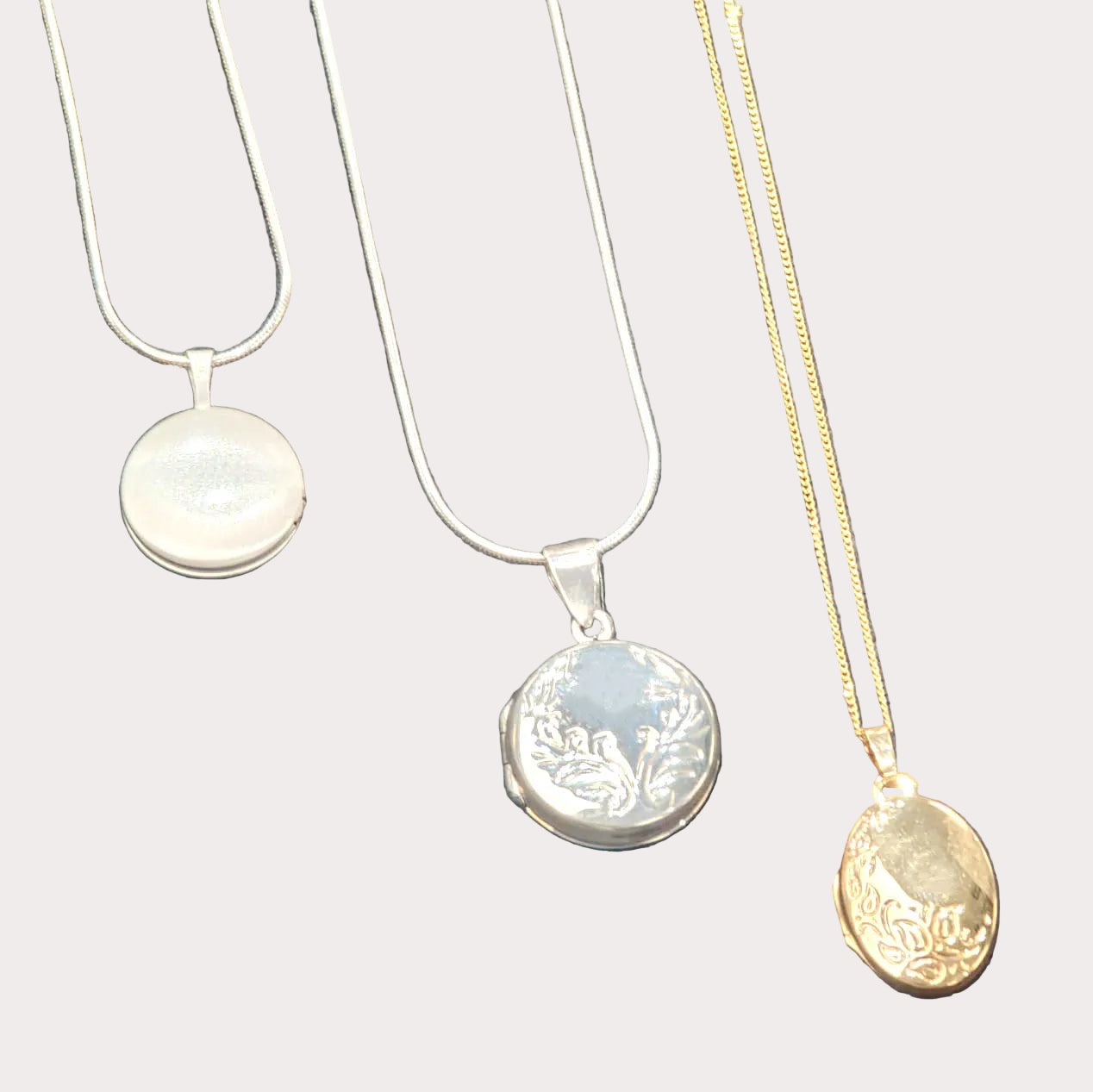 Three necklaces with different pendants on a gray surface